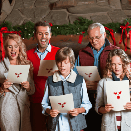 A family singing Christmas carols with music sheets in their hand.