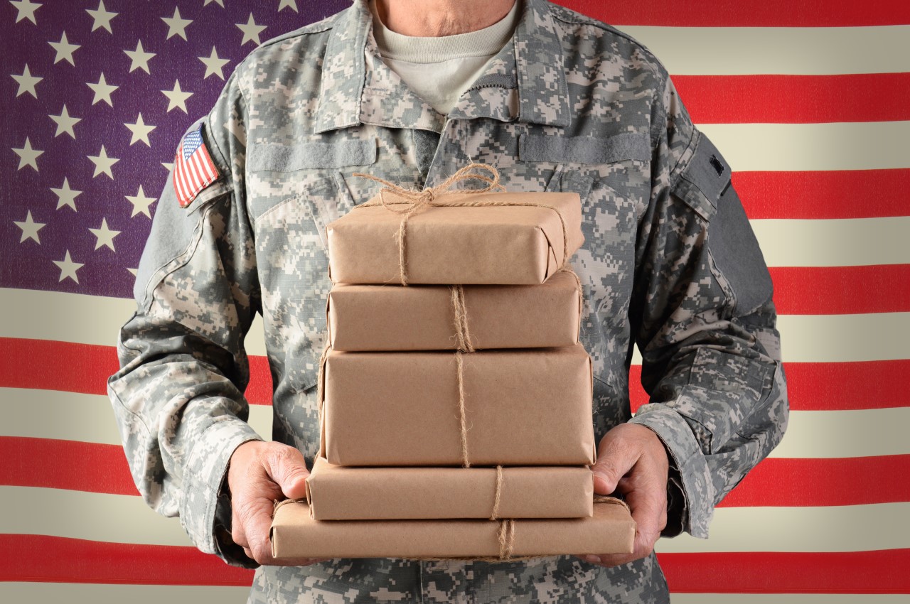 soldier holding boxes in front of american flag