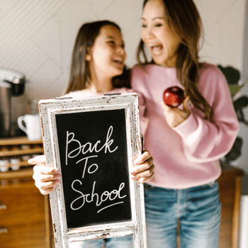 A mom and her daughter holding a back to school sign.