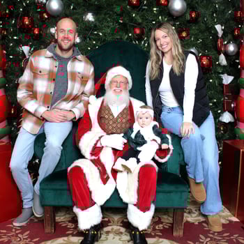 A mom and dad with their little girl sitting with Santa.