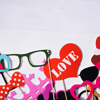 Photo booth props that include glasses, a red heart that says "love" and more.