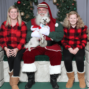 A white dog sitting with Santa and his family.