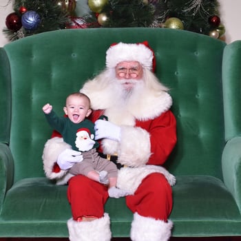 Baby smiling with fist in the air with Santa.