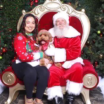 Santa with a girl and her dog with a bow.
