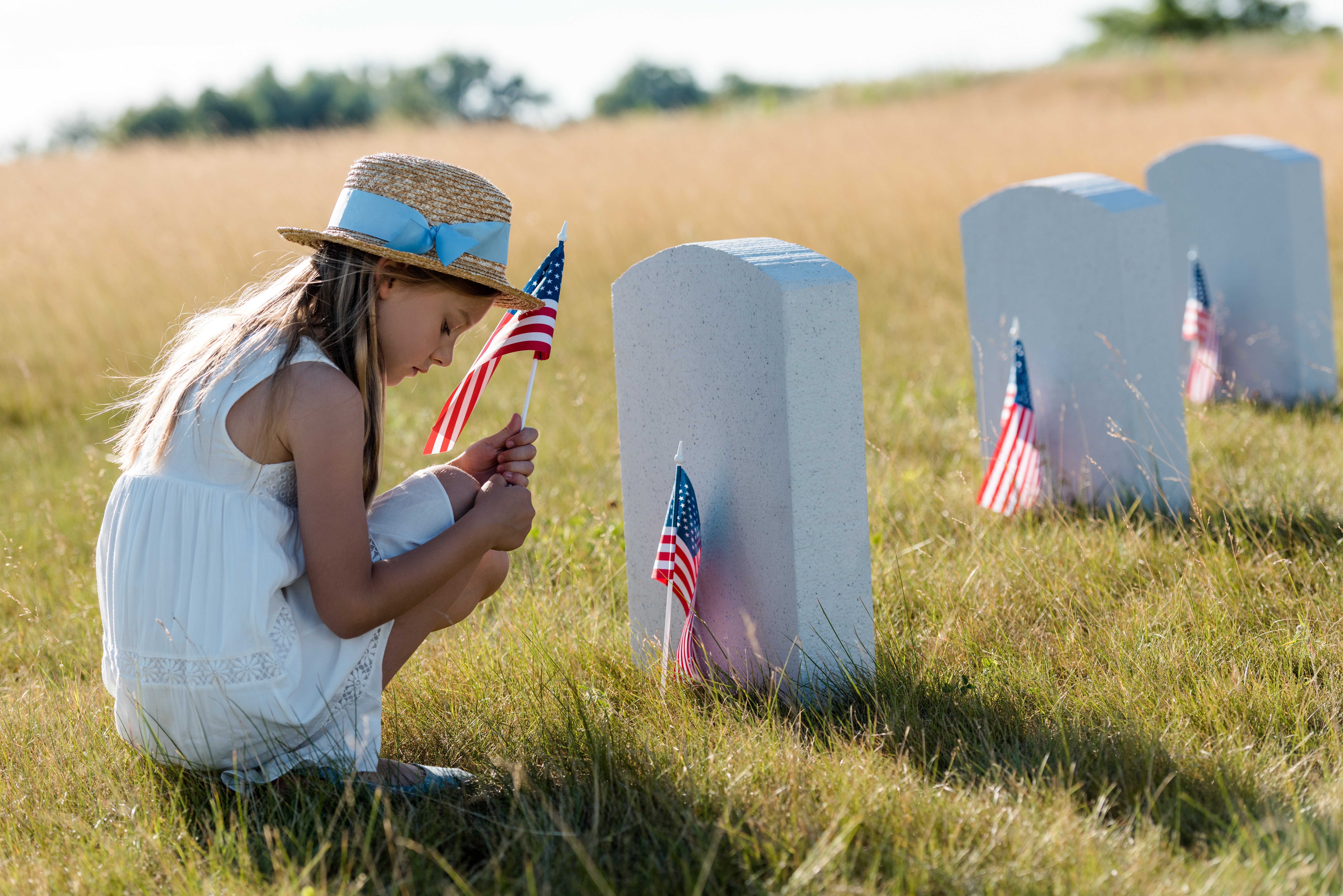young-girl-in-front-of-grave-gravestone-memorial-day-american-flag-soldier-graveston