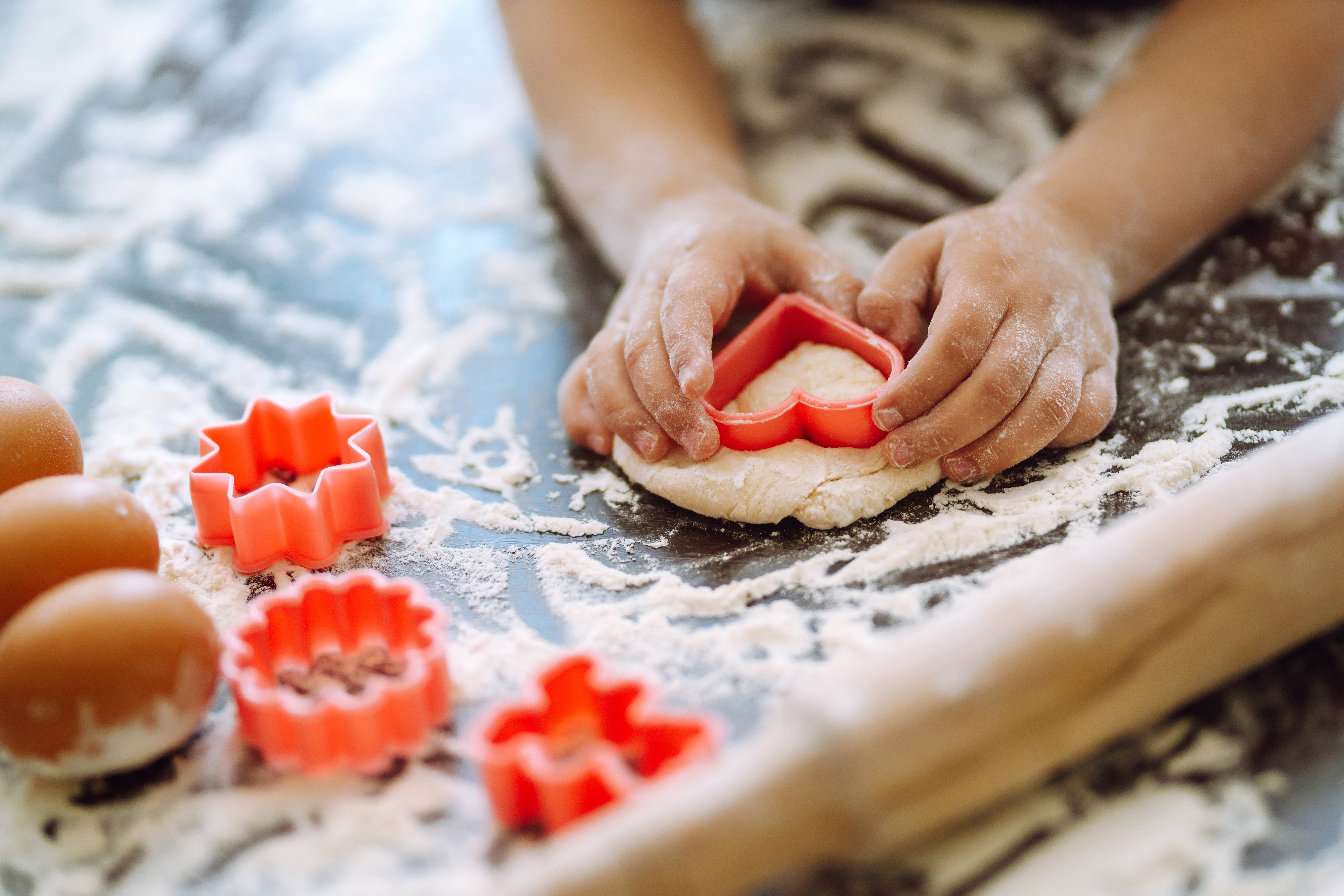 child using cookie cutter to shape dough to help family prepare holiday meal