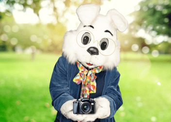 Easter Bunny holding a camera in a park for national photography month
