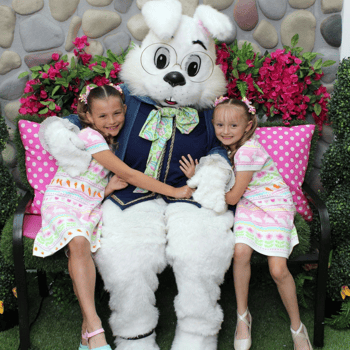 Two little girls in matching dresses hugging the Easter Bunny.