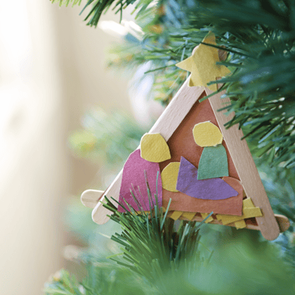 A child made ornament hanging on a Christmas tree.