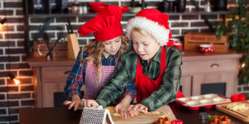 two children rolling dough at christmas time to make holiday treats
