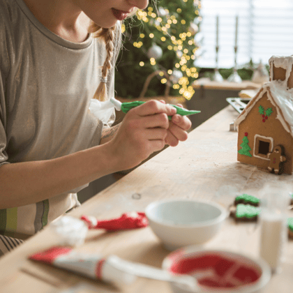 A girl decorating a gingerbread house.