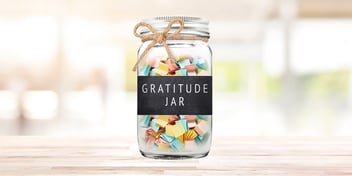 how to make a gratitude jar with your family. glass jar with handwritten notes inside, tied with twine.