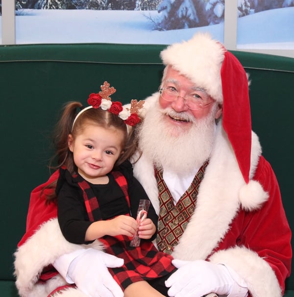 3 year old girl sitting with Santa during Santa Cares event