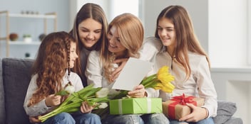 women-on-couch-sofa-exchanging-mothers-day-gifts-and-flowers-mom