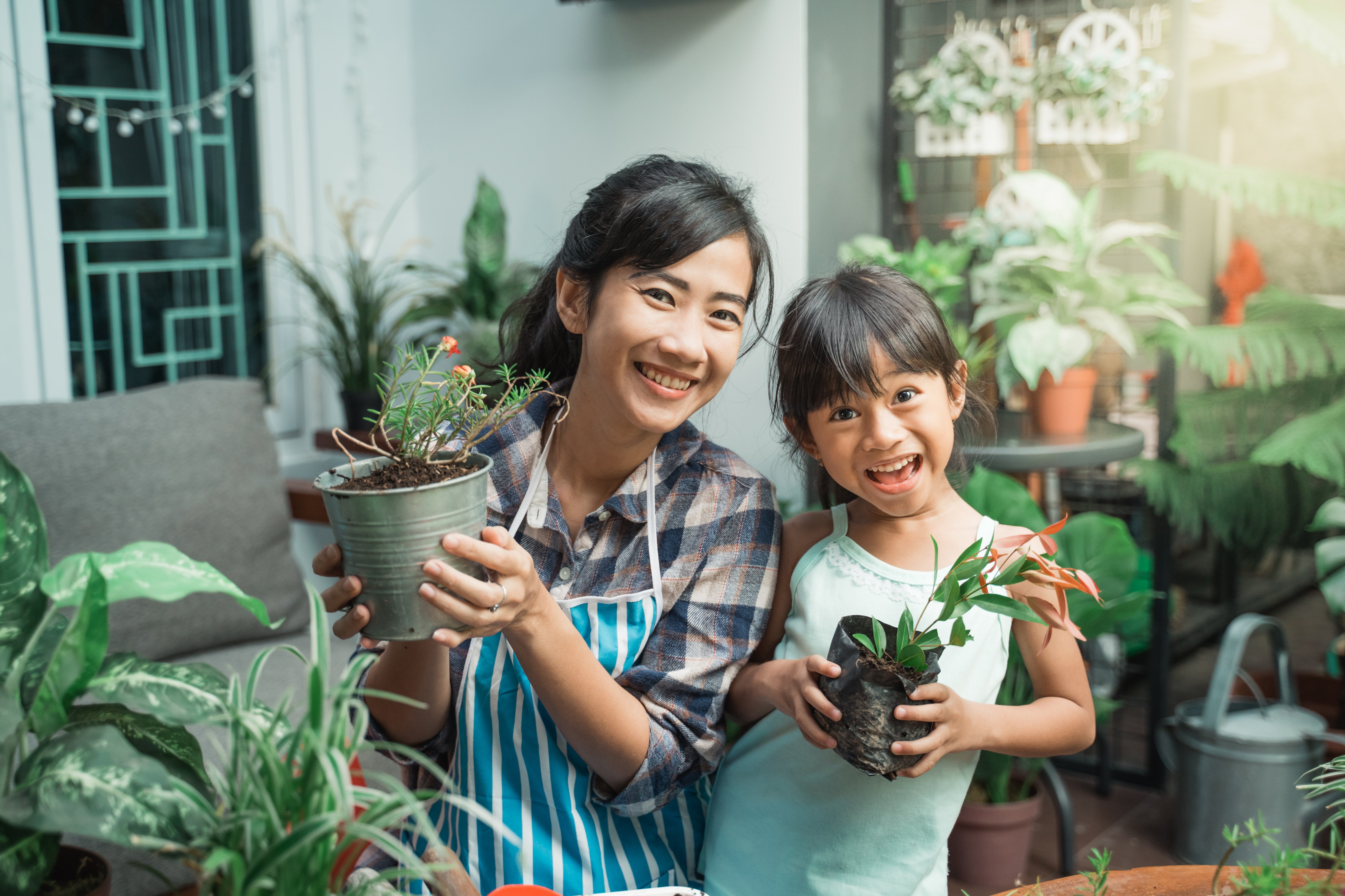 mother and daughter gardening potted plants green thumb smiling