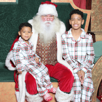 Two little boys sitting with Santa in Christmas Pajamas.