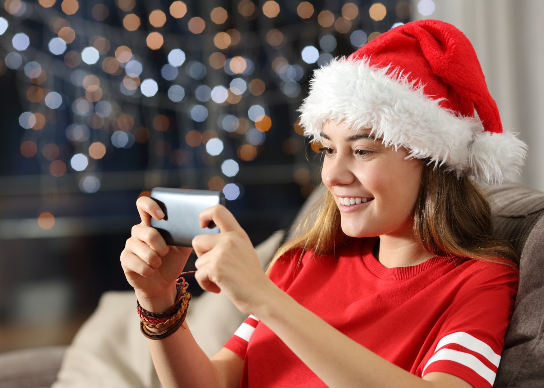 Teen girl looking at a device and wearing a Santa hat