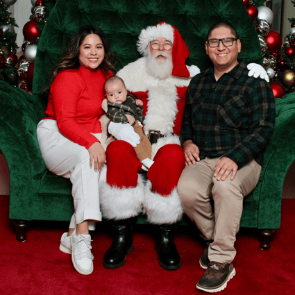 Photo of family wearing classic Christmas colors. Mom in a red sweater and white pants. Dad and baby are in green flannels and khakis.