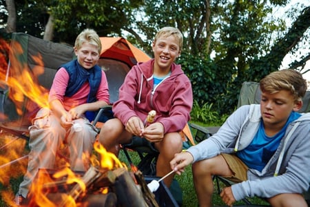 boys toasting marshmallows around campfire