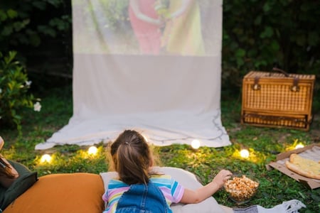 child enjoys movie night outdoors with picnic