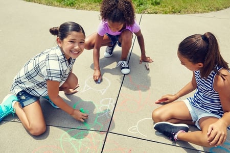 children drawing with chalk on suburban sidewalk