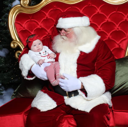 Baby in a festive outfit with Santa.