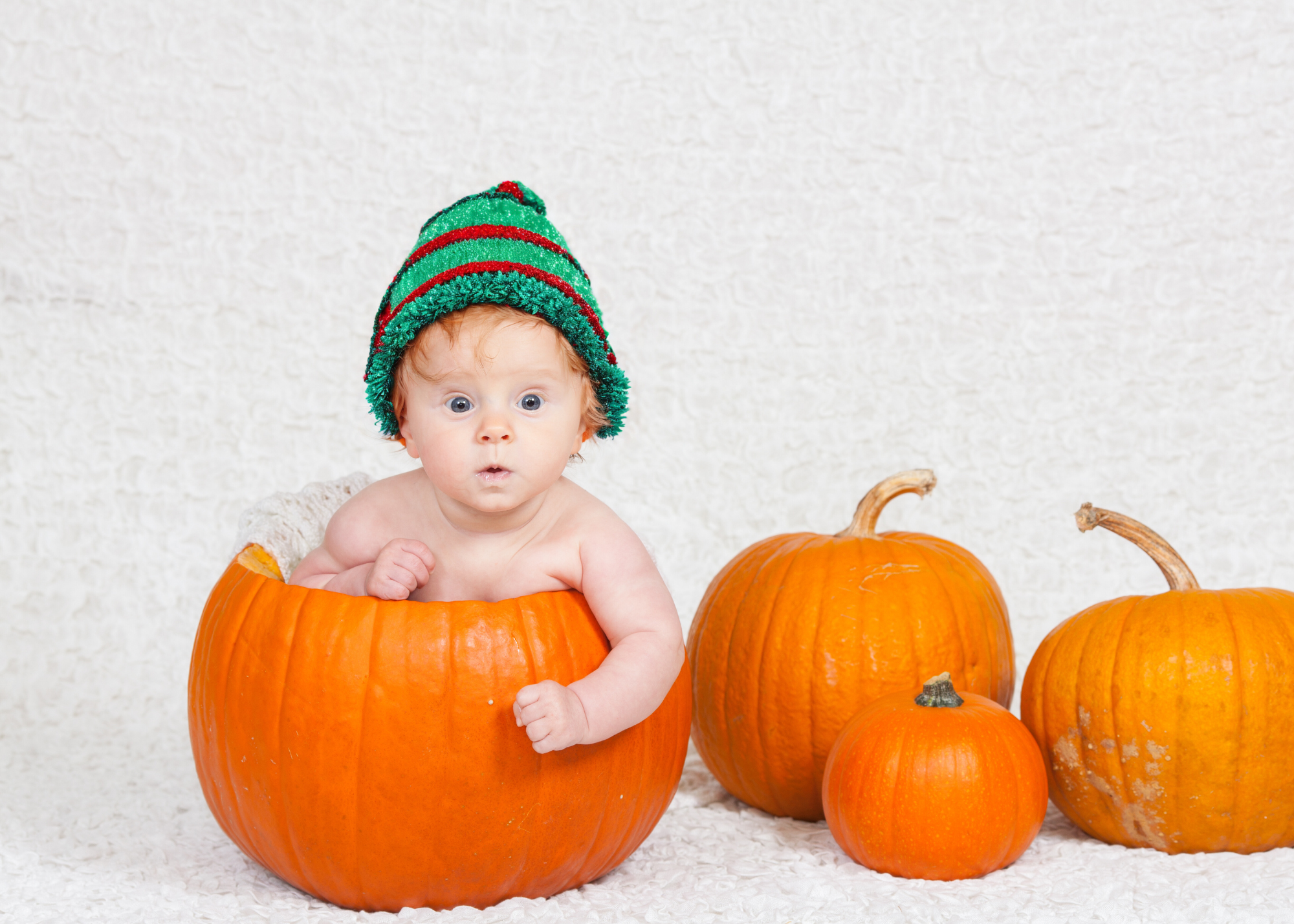 baby in elf hat sitting inside pumpkin