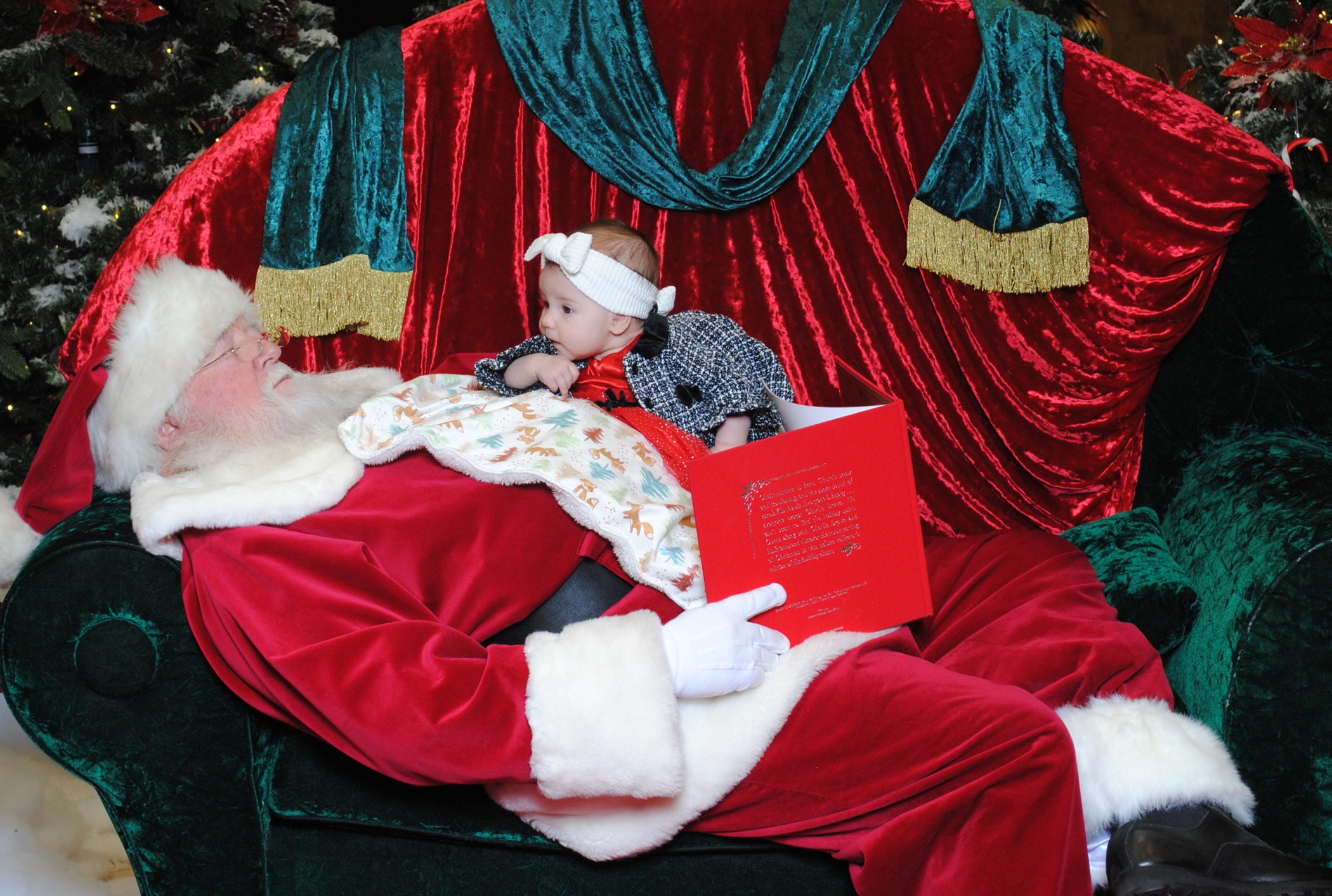 Santa Claus calls asleep while reading a book to a baby