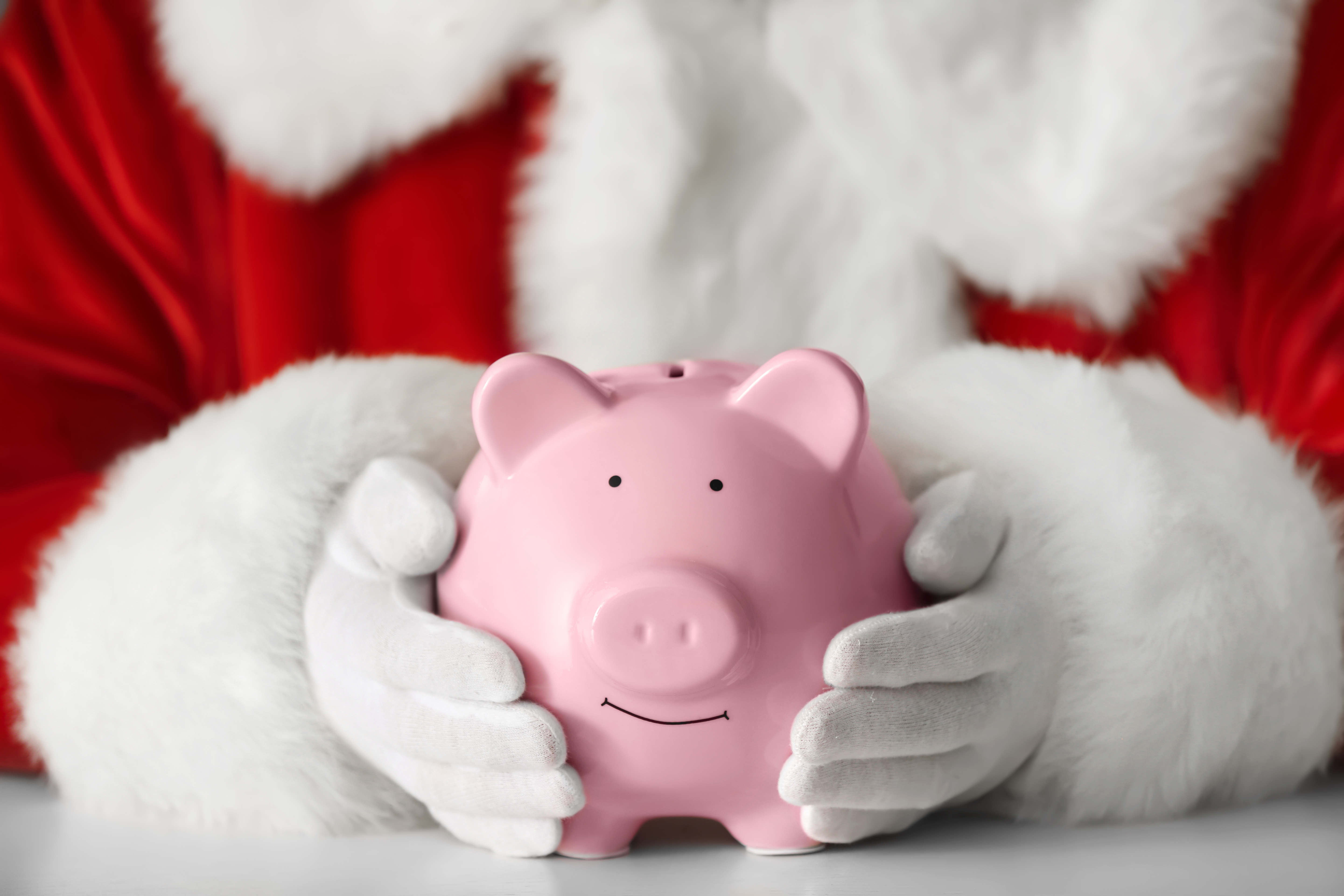 close up of Santa's hands holding a piggy bank